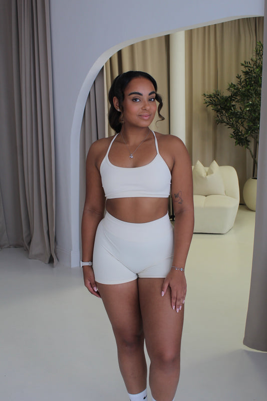 Young woman in Ilume Collection Scrunch Bum Gym Shorts, standing in a minimalist space, showcasing the shorts' high-waisted design and flattering fit.