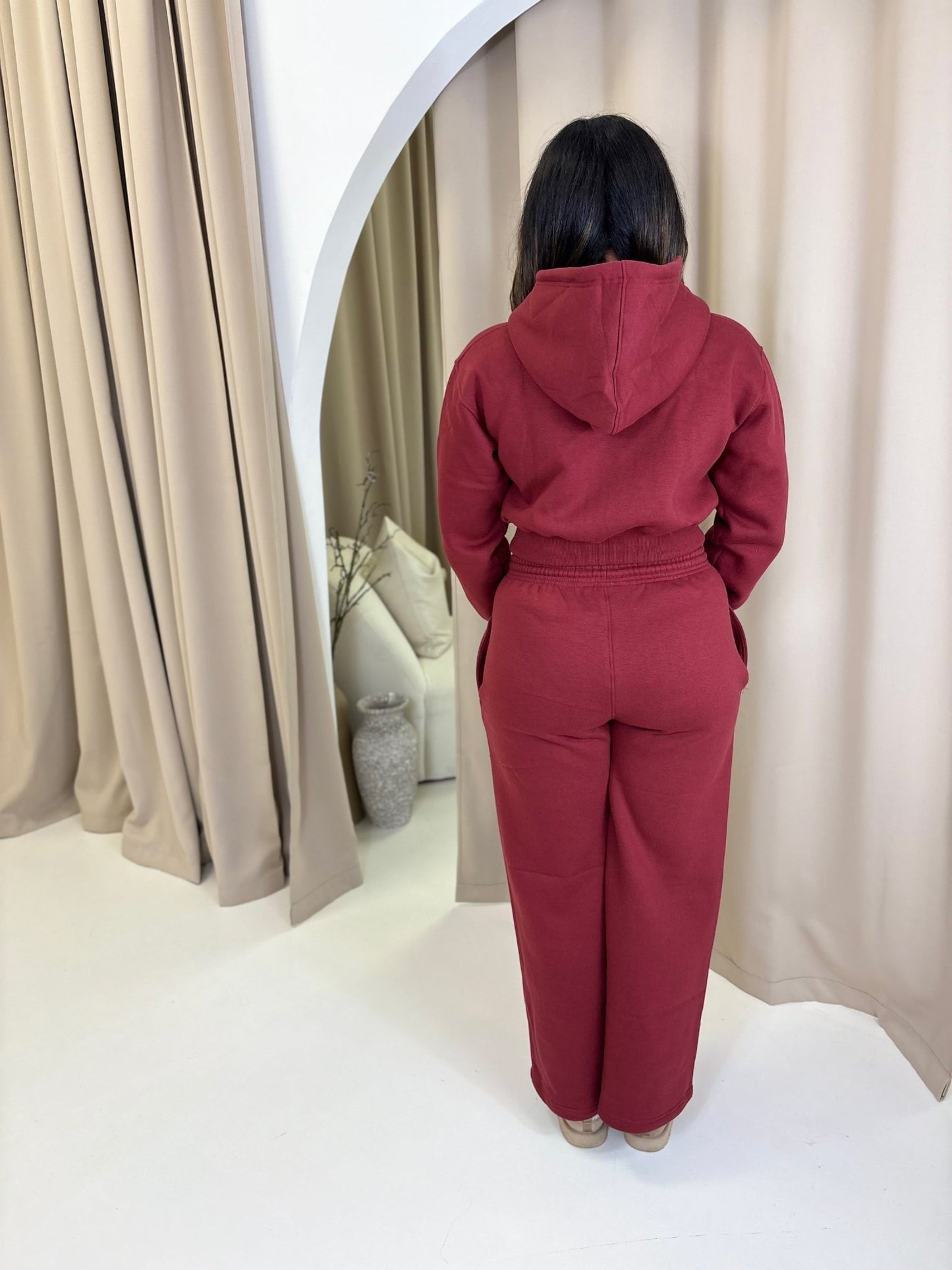 Person wearing the Elena Lounge Fit Matching Tracksuit Jacket, showcasing its relaxed fit and wide-leg style in a modern, minimal room with reflective decor.