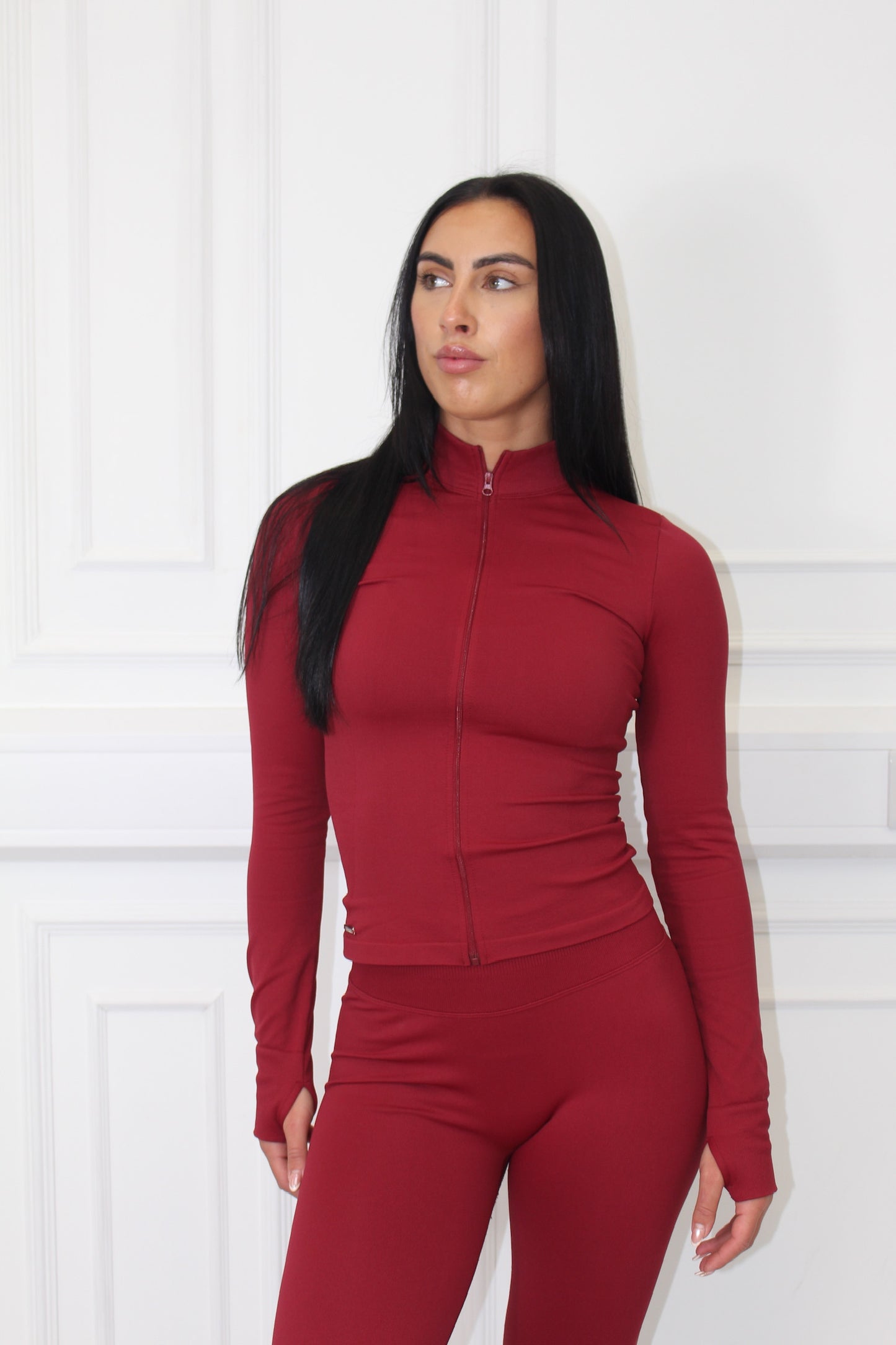 The Empower Edge Collection - Gym Jacket features a woman in a red zip-up top, showcasing a sleek, curve-hugging design ideal for workouts.