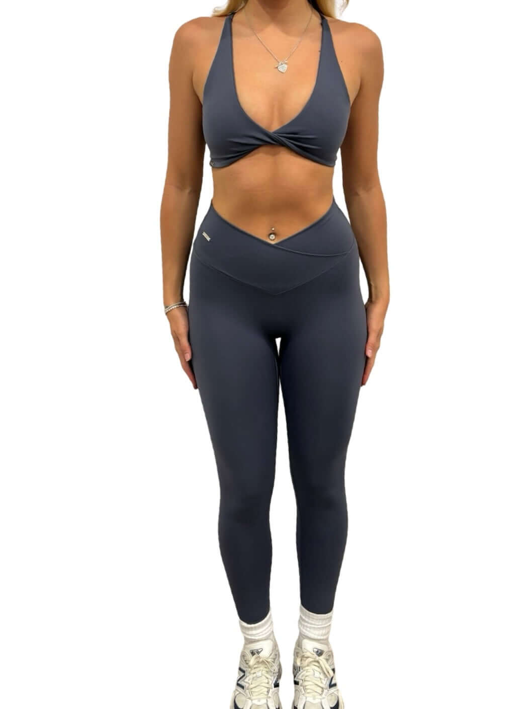 Woman wearing Pilates Reformer Collection high-waisted wrap front leggings, paired with white tennis shoes, showcasing a stylish and supportive gym outfit.