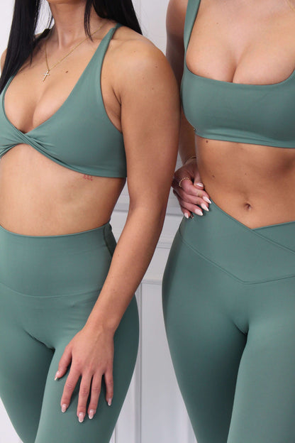 Two women modeling Pilates Reformer Collection's high-waisted wrap front gym leggings, showcasing a supportive fit and stylish design.