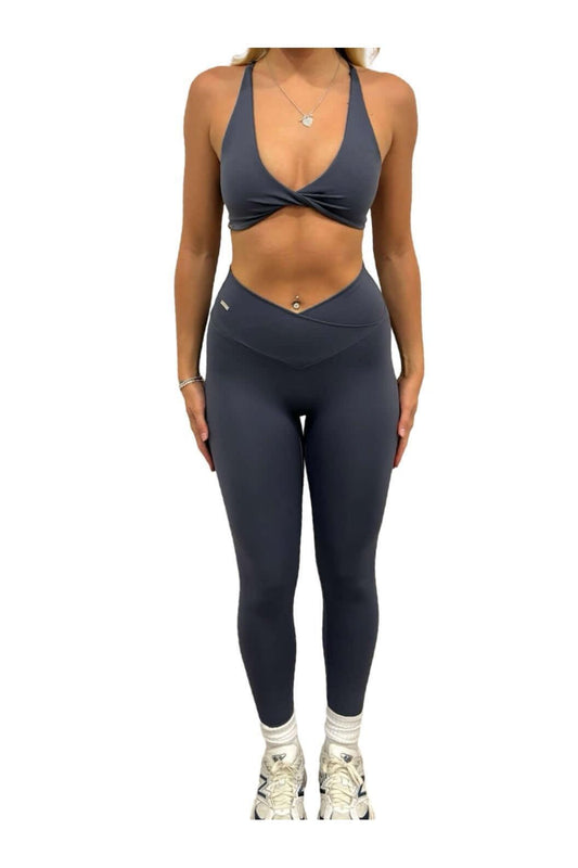 Woman wearing Pilates Reformer Collection high-waisted wrap front leggings, paired with white tennis shoes, showcasing a stylish and supportive gym outfit.