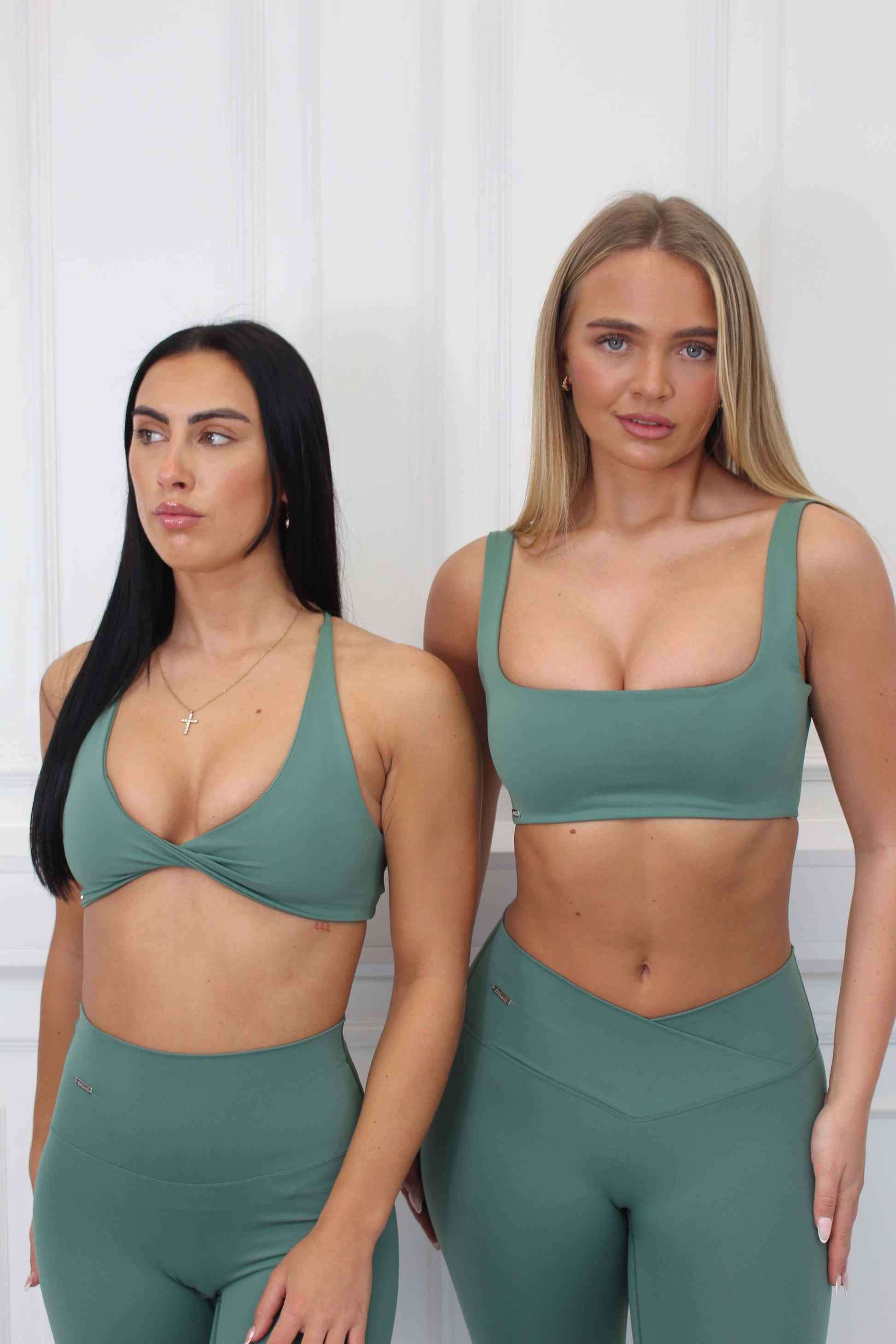 Two women wearing the Pilates Reformer Collection Twist Front & Cross Back Bra, showcasing stylish support and comfort for fitness activities.