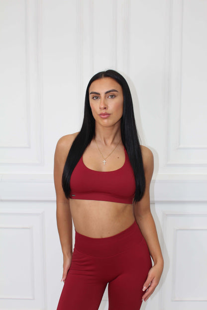 A young woman models The Edge Collection Gym Bra, showcasing its personalized fit and curve control against a white paneled wall.