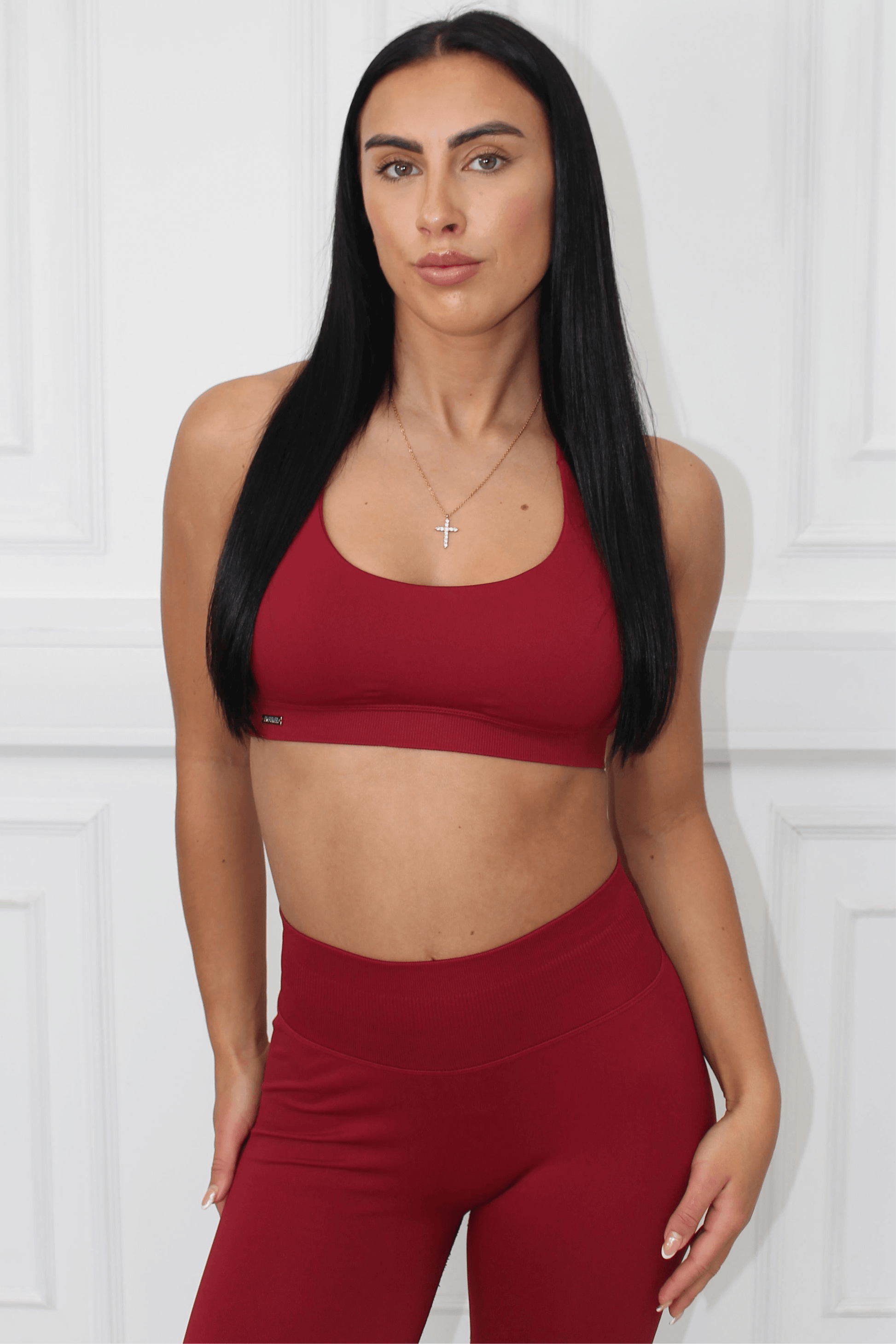 Young woman models The Edge Collection - Lightweight Summer Vest, showcasing a deep-red workout set: scoop-neck sports bra and high-waisted leggings, emphasizing luxury and comfort.