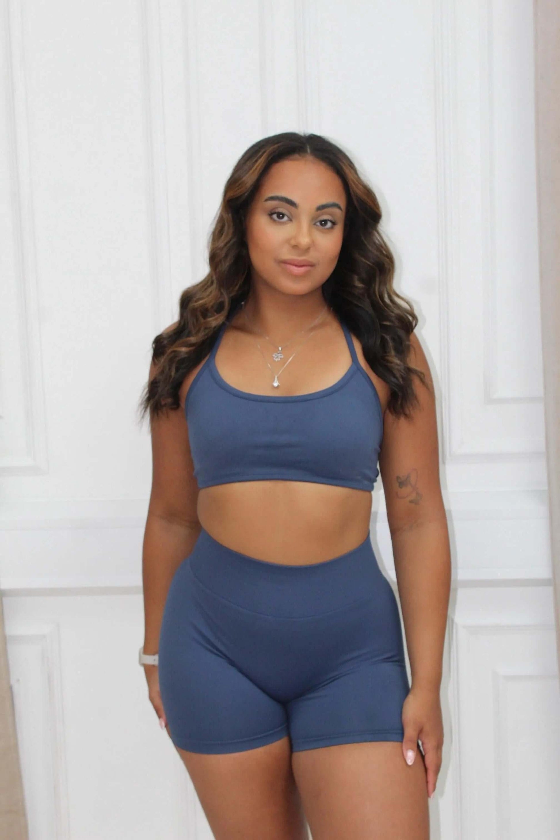 Young woman models The Ilume Collection Scrunch Bum Gym Shorts, showcasing flattering fit and high-waisted design, paired with a matching cropped sports bra.