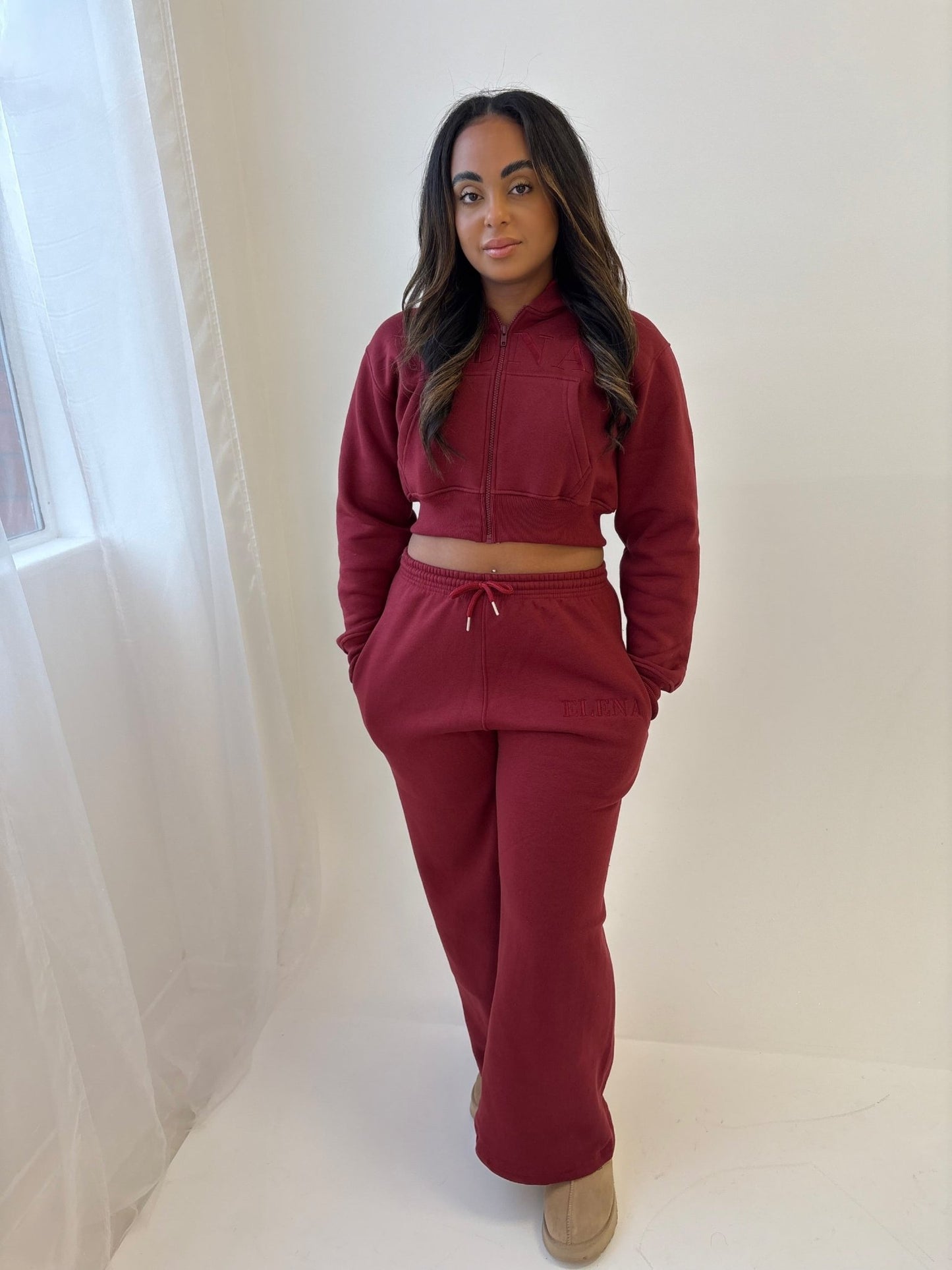 Young person models the Elena Lounge Fit Matching Tracksuit Jacket, featuring a cropped hoodie and relaxed sweatpants, with ELENA stitched on the hip.