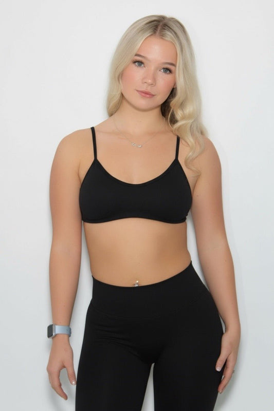 Young woman wearing The Eclipse Collection - Gym Bra, showcasing a stylish and supportive design ideal for workouts, paired with high-waisted leggings and a smartwatch.