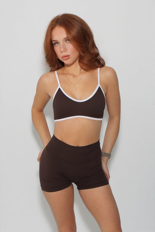 Woman wearing The Eclipse Collection - Scrunch Bum Gym Shorts, featuring a snug, high-waisted fit with white trim, accessorized with a necklace and watch.