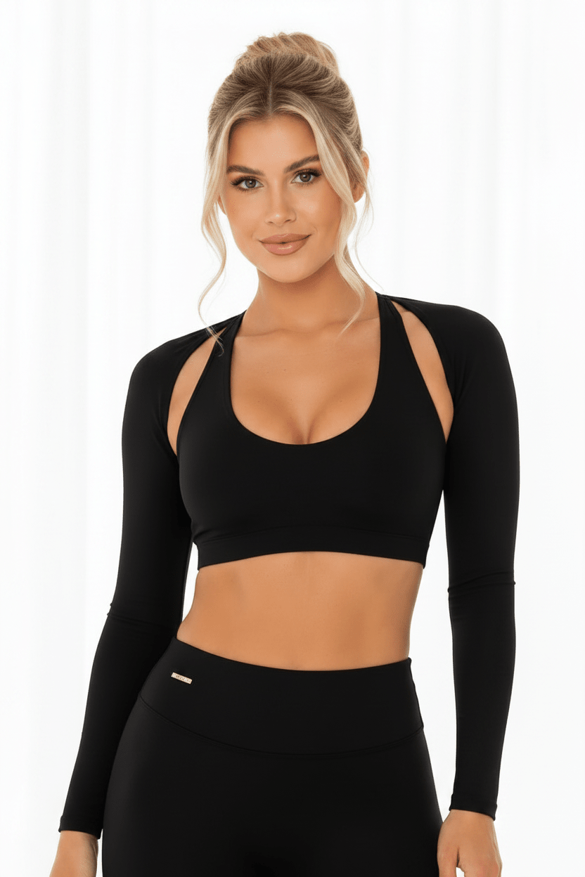 The Elena Soft Core Collection - The Gym Shrug: A young woman wears a black shrug with cut-out shoulders, ideal for comfortable, breathable workouts.