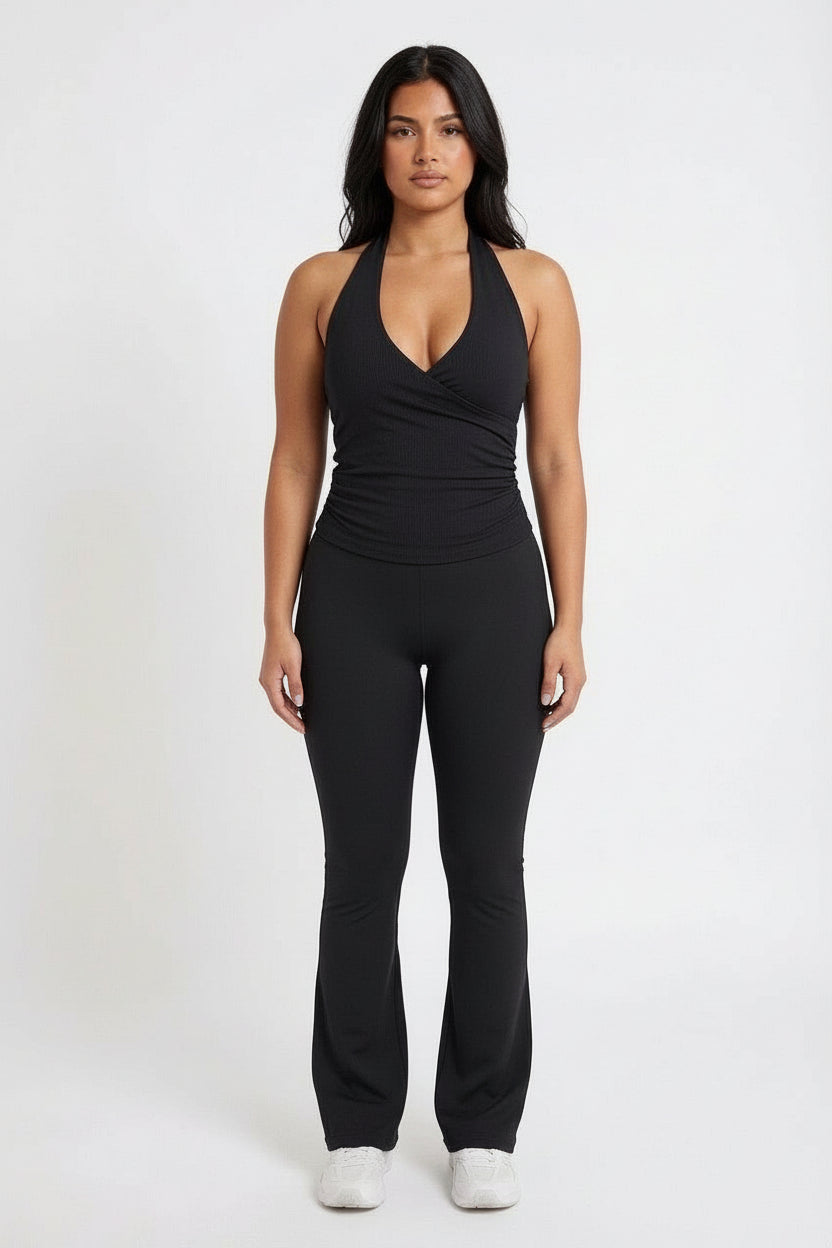 Woman wearing The Elyse Collection Longline Wrap Gym Top with high-waisted flared yoga pants and chunky sneakers, showcasing a chic, comfortable workout look.