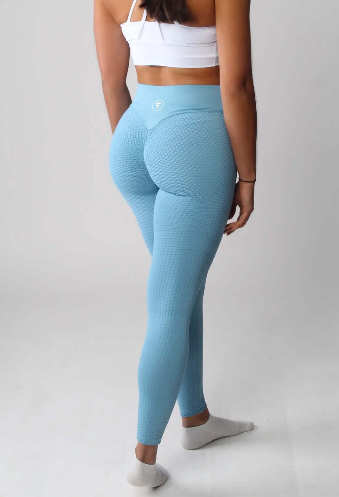 The Nova Honeycomb Scrunch Collection leggings, featuring a high-waisted, contouring design with scrunch bum detail and pocketed options, showcased on a model's waist.